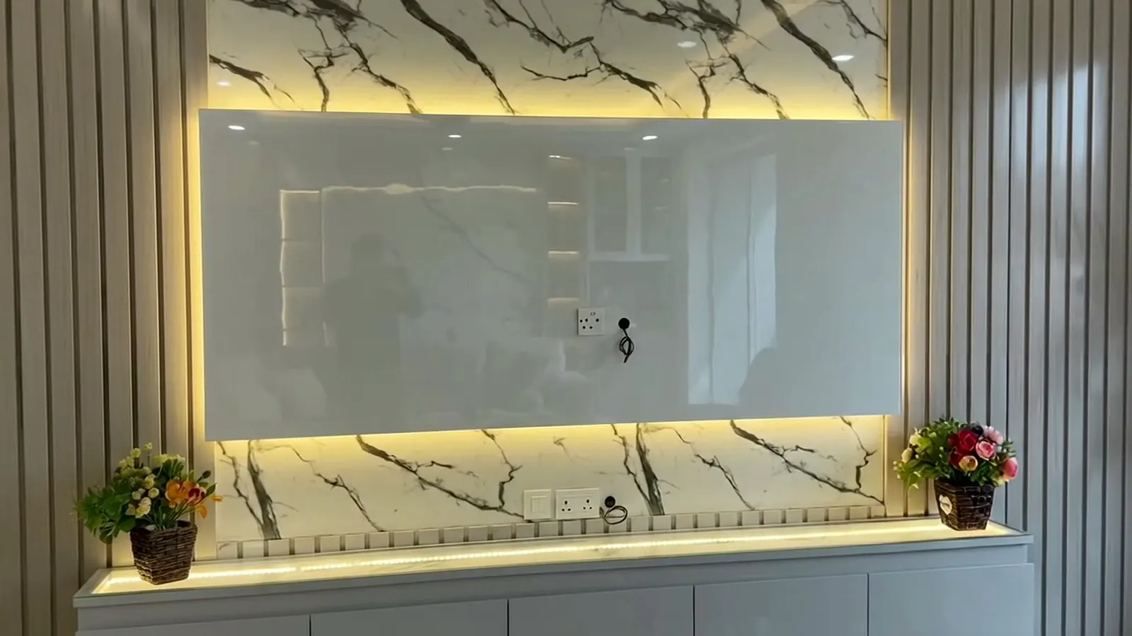 A TV wall finished with a marble-look UV sheet and fluted side panels